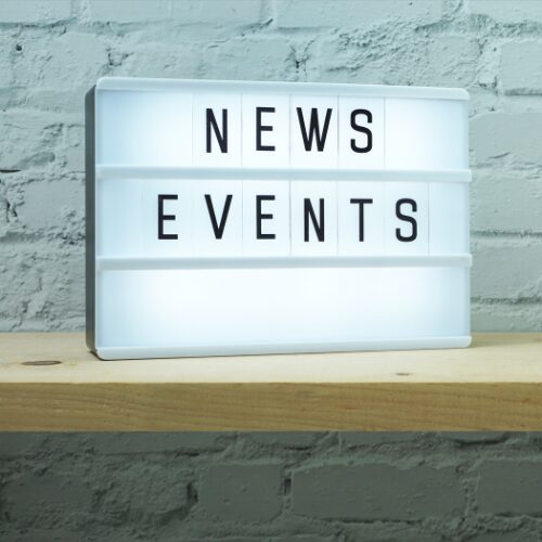 a sign that reads "news and events" sitting on a wooden board leaning against the wall