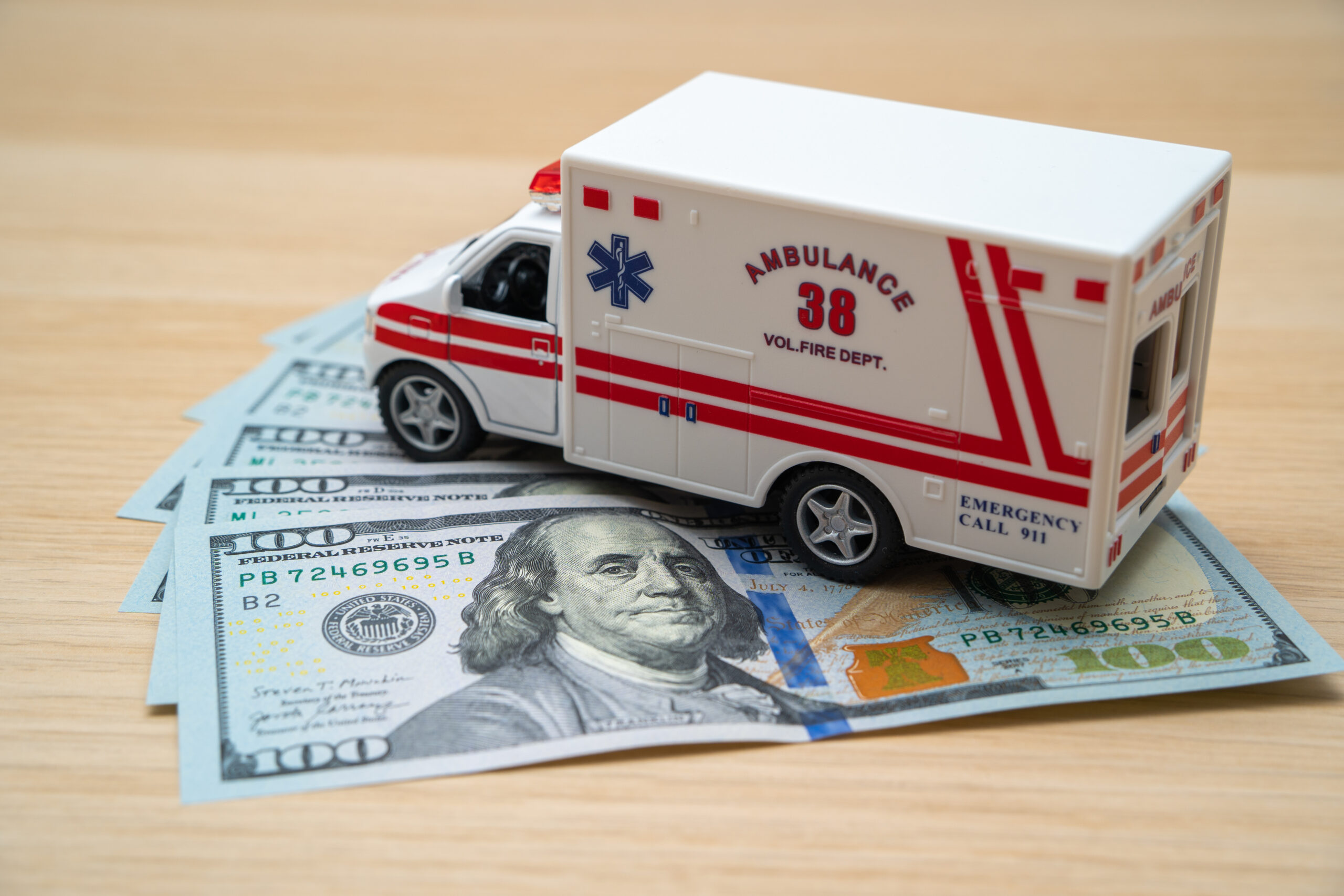 An ambulance parked overtop of money neatly spread out on a table